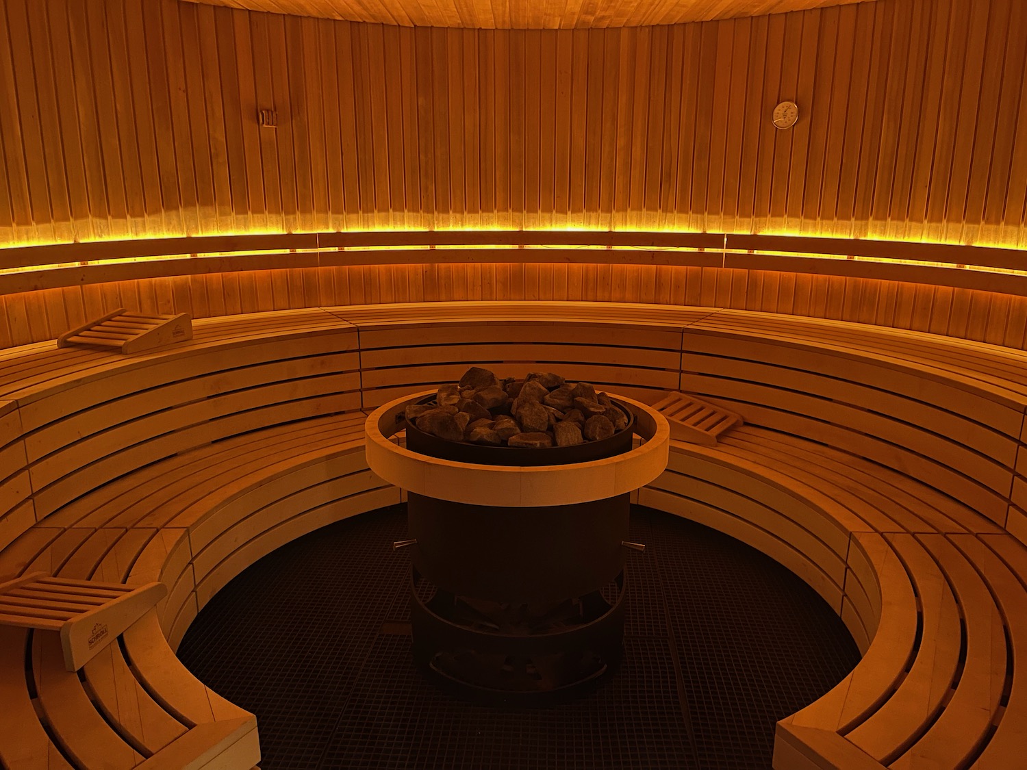 a round wood bench with a fire pit in a room with wood walls