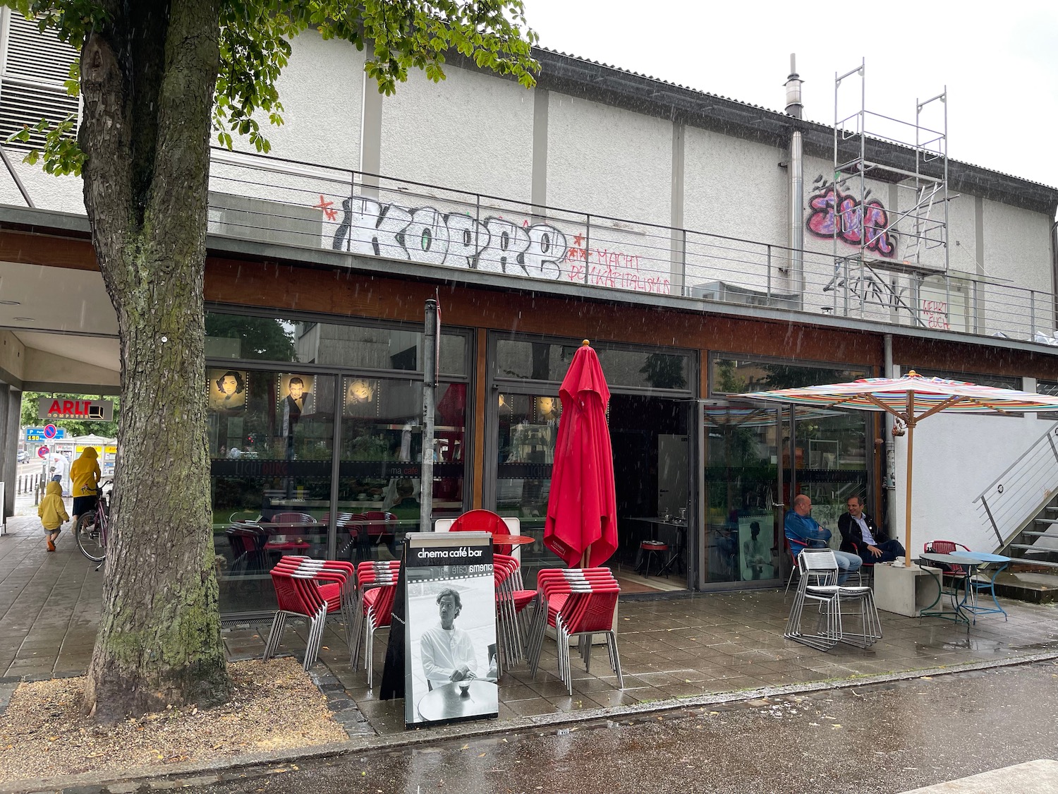 a building with red chairs and umbrellas