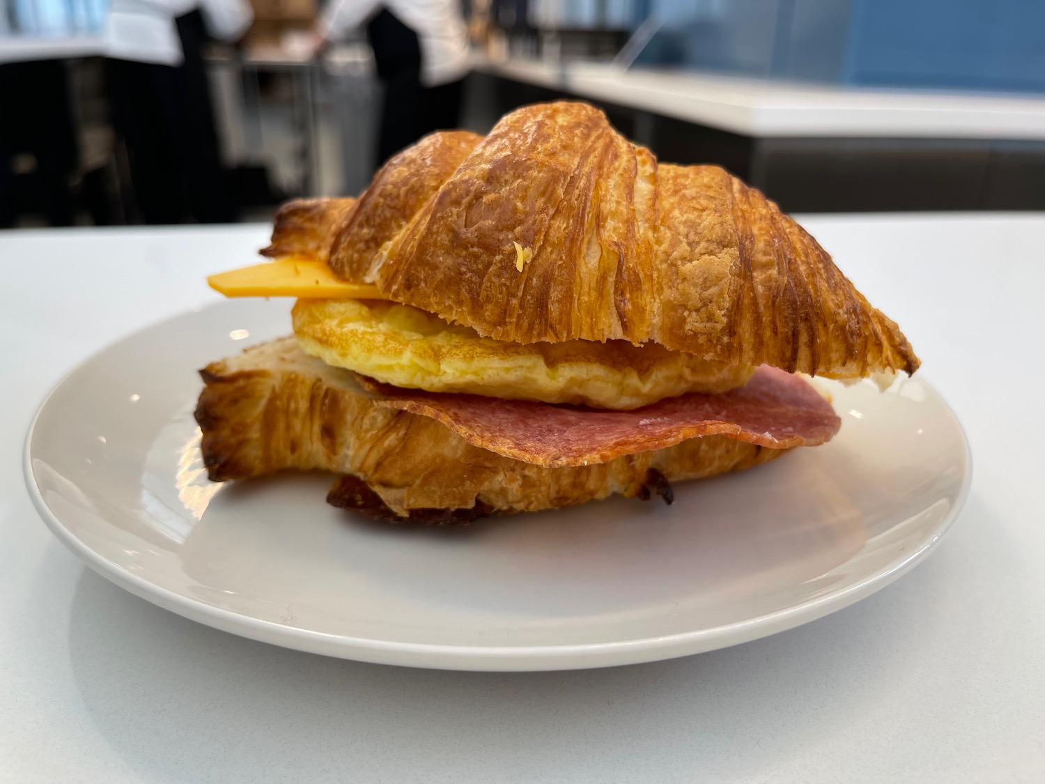 a croissant sandwich with ham and cheese on a white plate