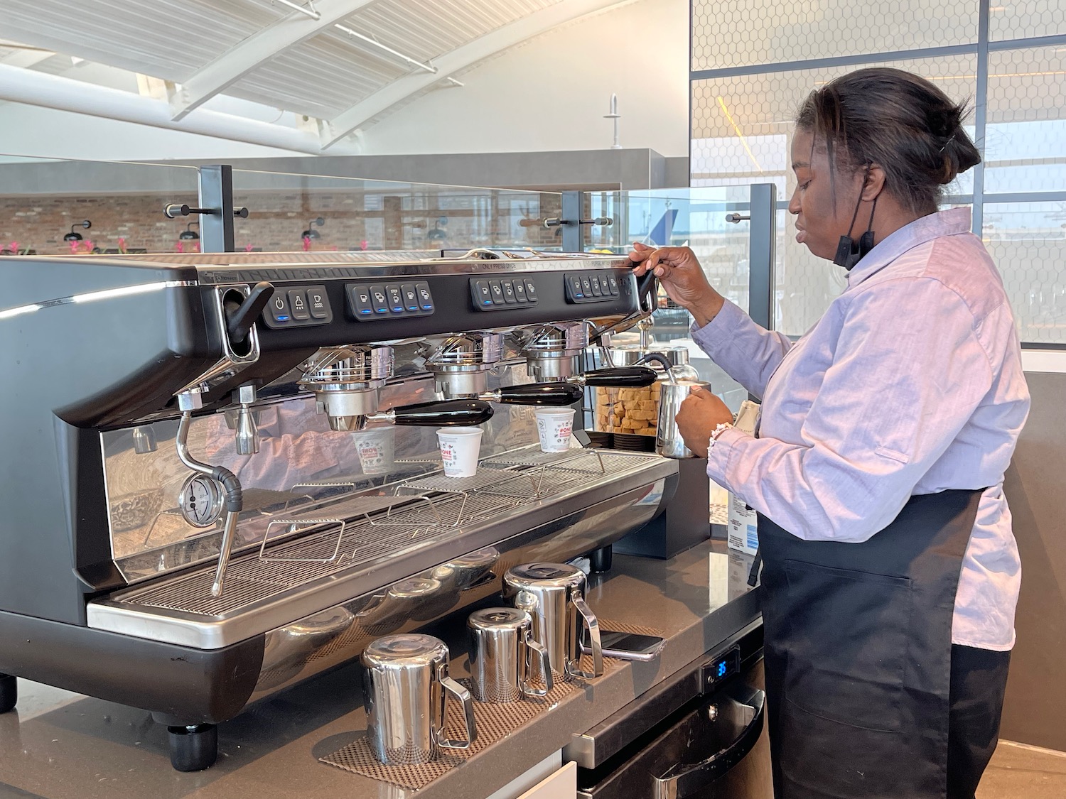 a woman making coffee at a coffee machine