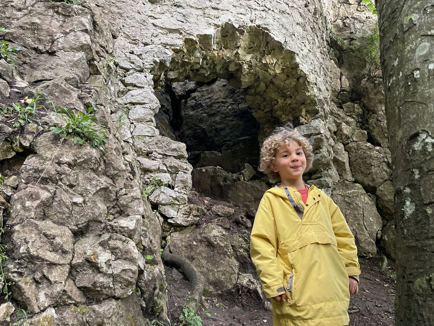 a child standing in front of a rock wall