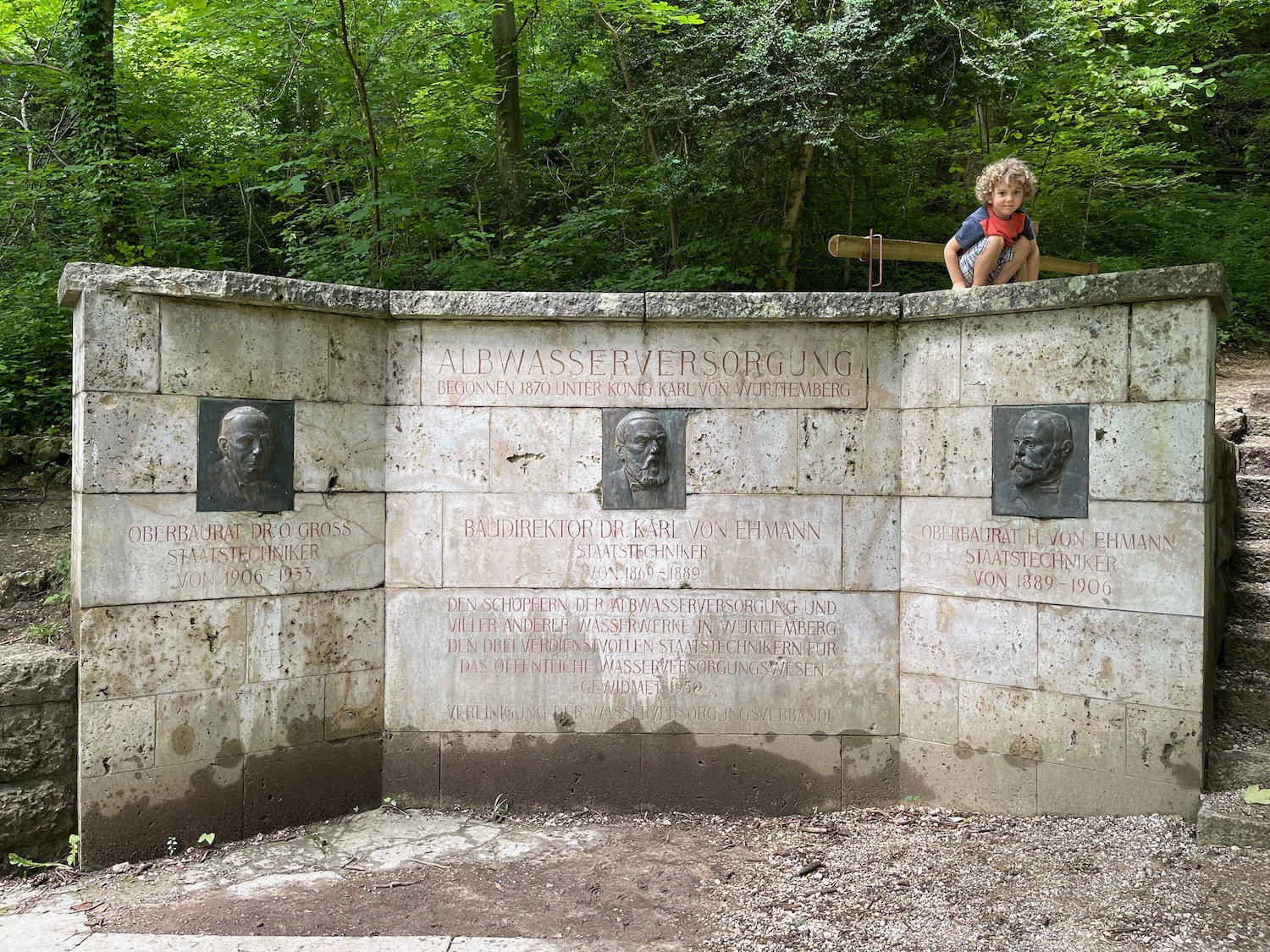a boy sitting on a wall with heads on it