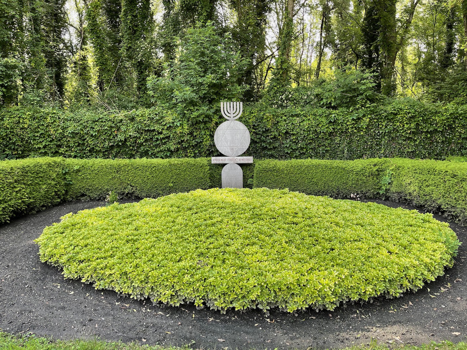 a stone statue in a circular hedge