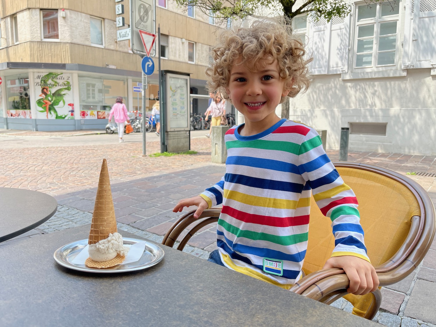 a child sitting at a table with ice cream cone on it