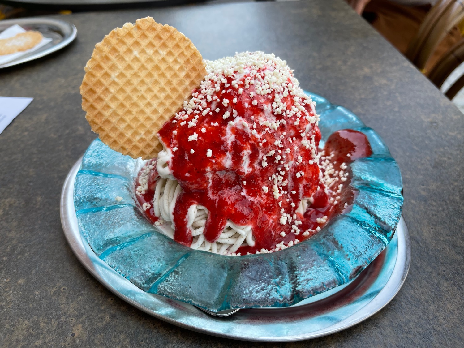 a bowl of ice cream with a waffle and a strawberry sauce