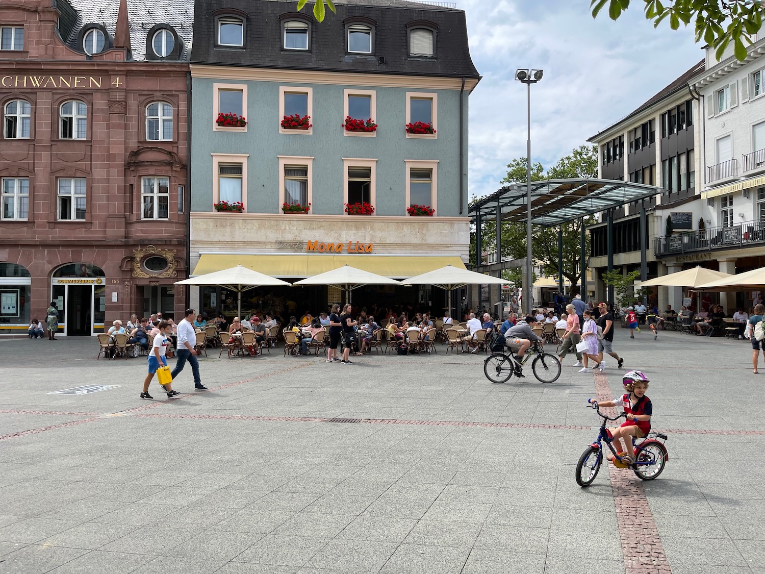 a group of people in a plaza with tables and chairs