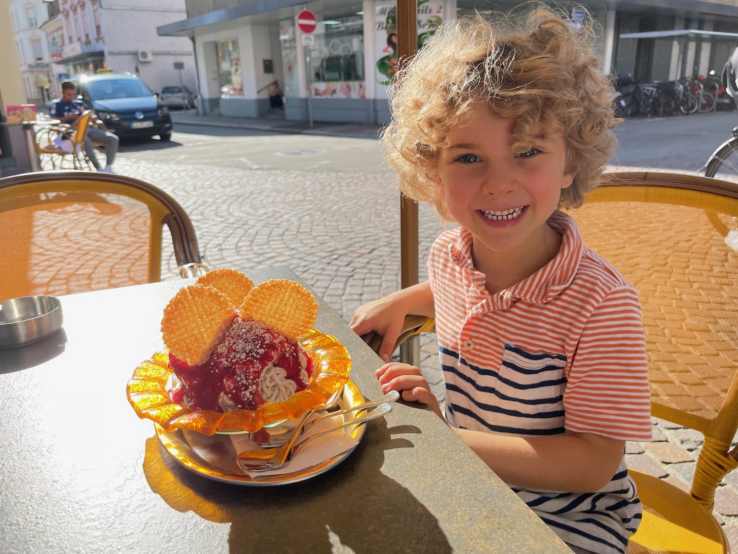 a child sitting at a table with a bowl of ice cream
