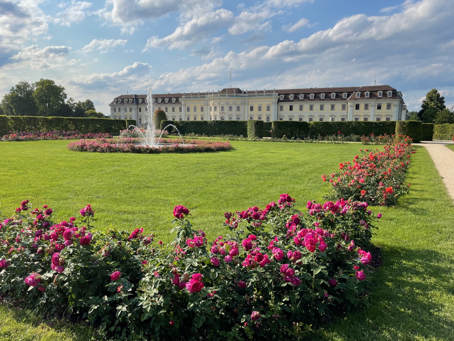 a large white building with a fountain in the middle of a green lawn