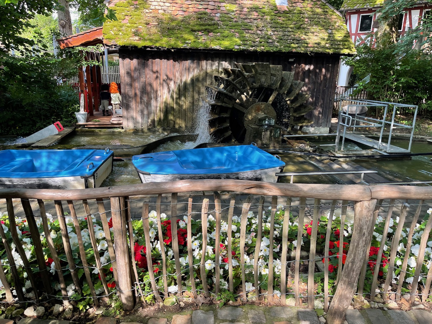 a water wheel with a water mill in the background