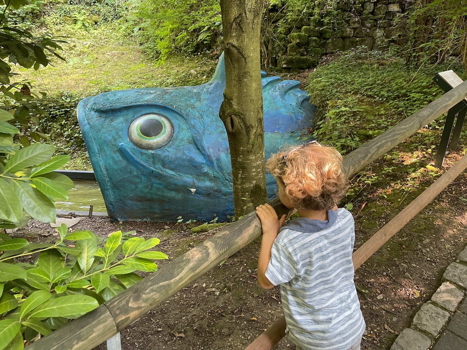 a child looking at a blue statue of a fish