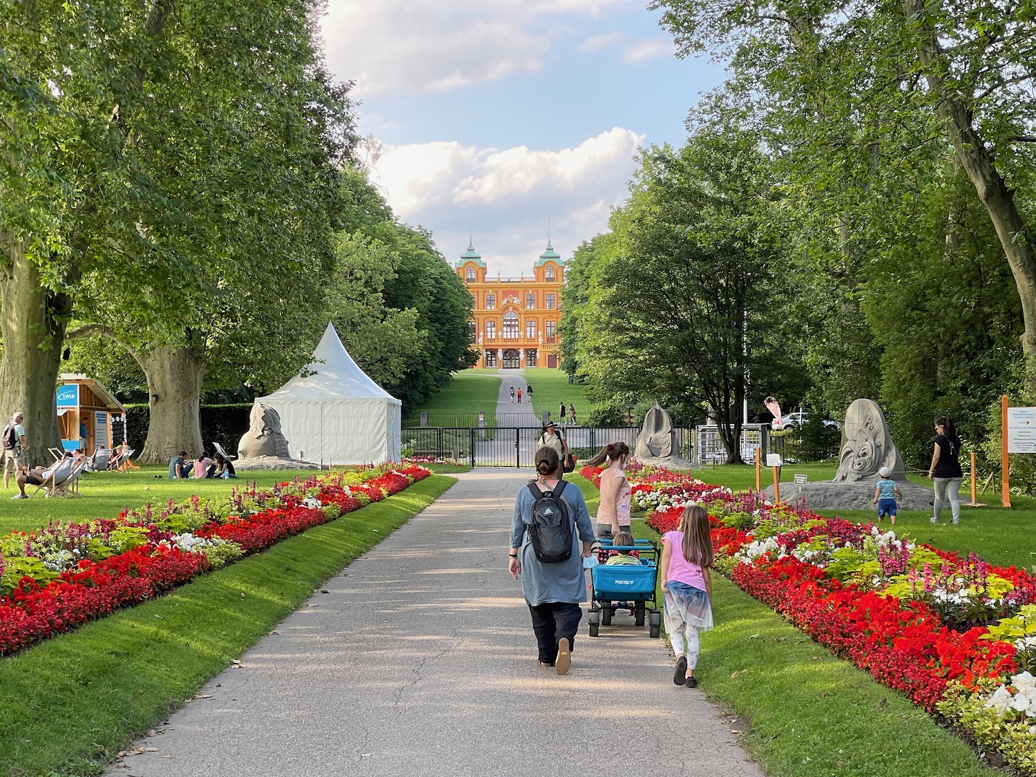 a group of people walking down a path with flowers and trees