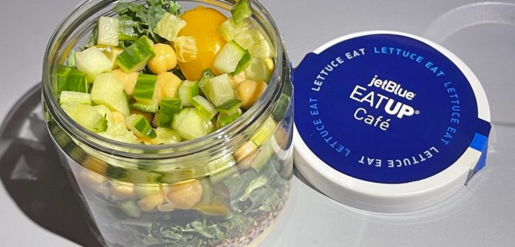 a jar of salad with vegetables and a blue lid