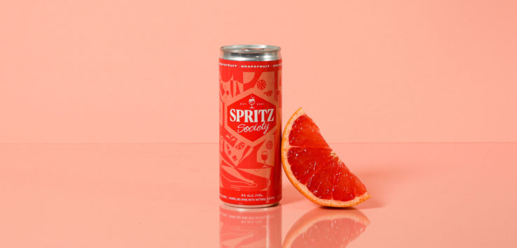 a can of soda next to a slice of orange