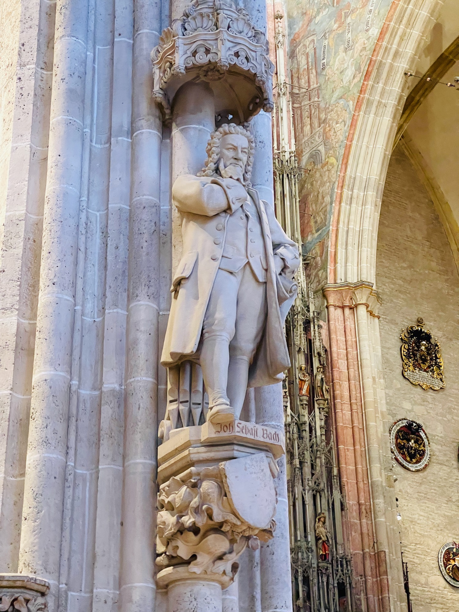 a statue of a man in a coat and coat on a pillar in a building