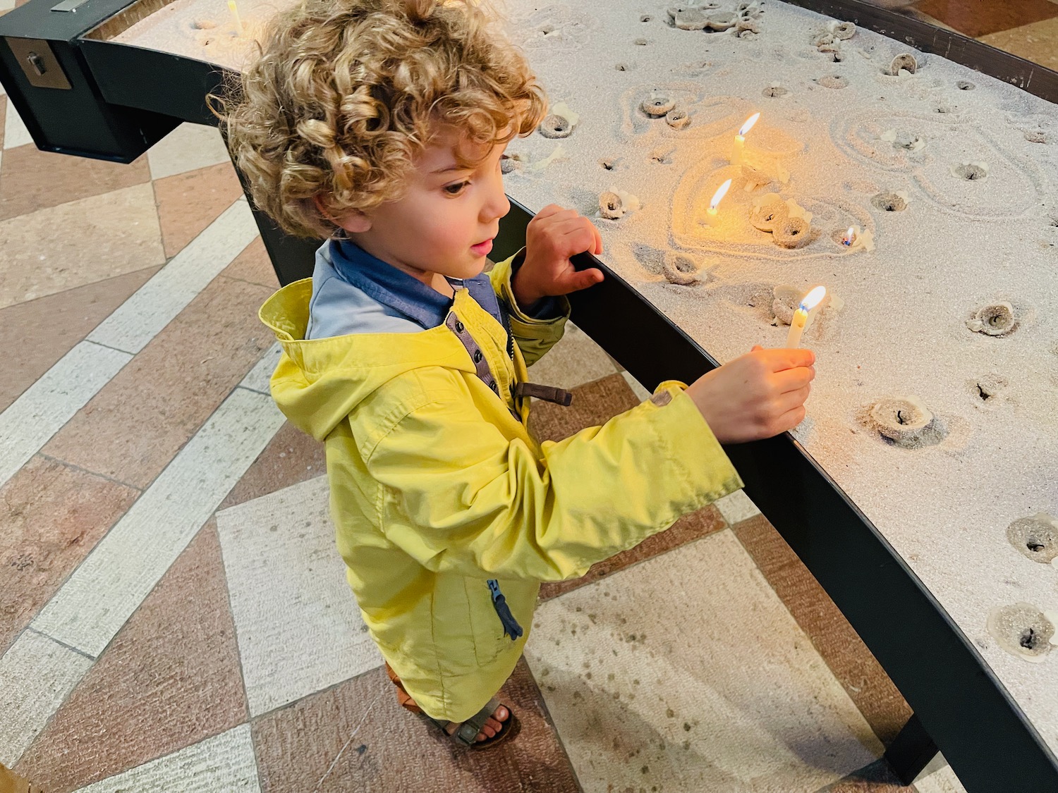 a child standing in sand with candles on it