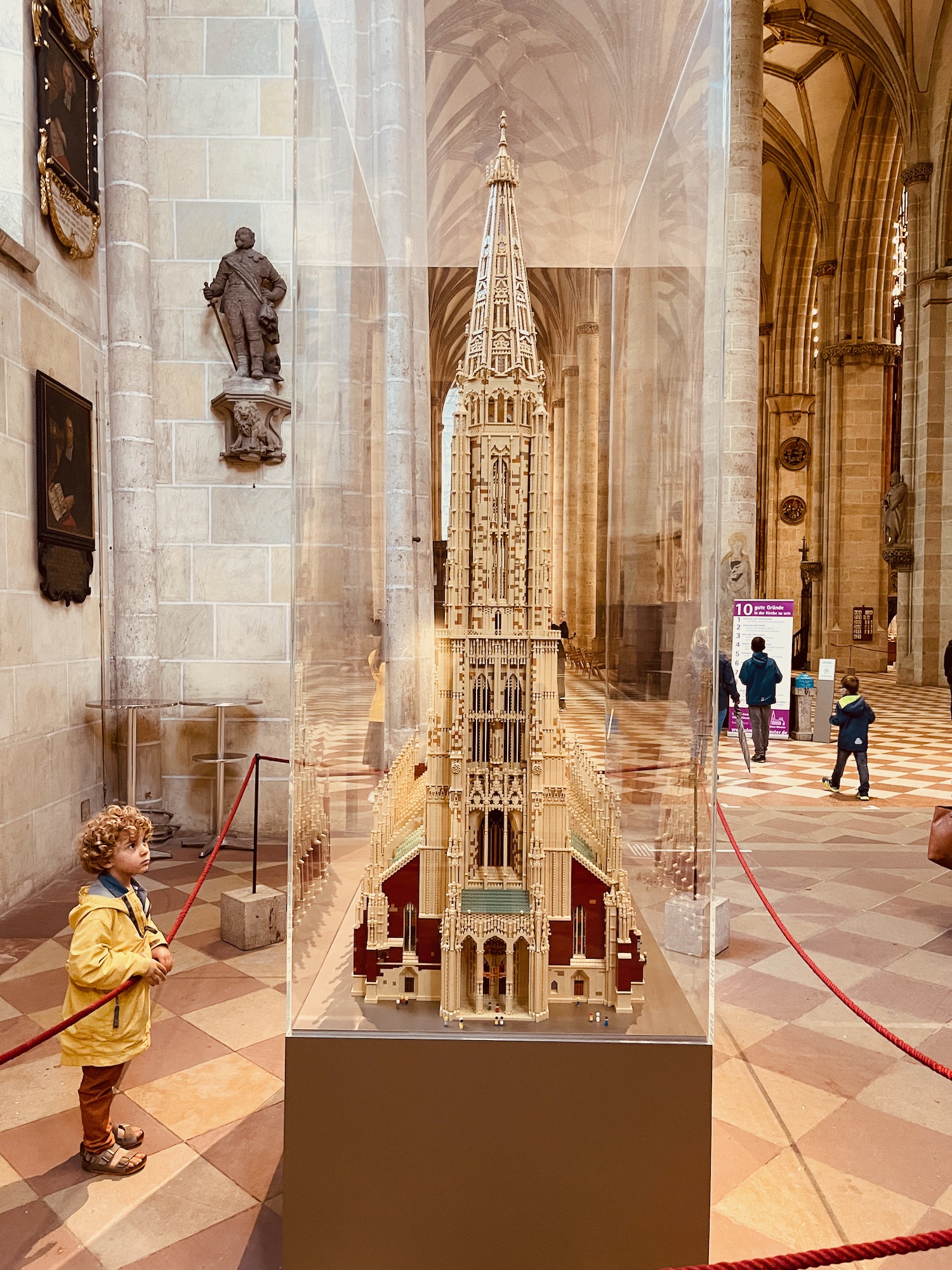 a boy looking at a model of a cathedral in a glass case