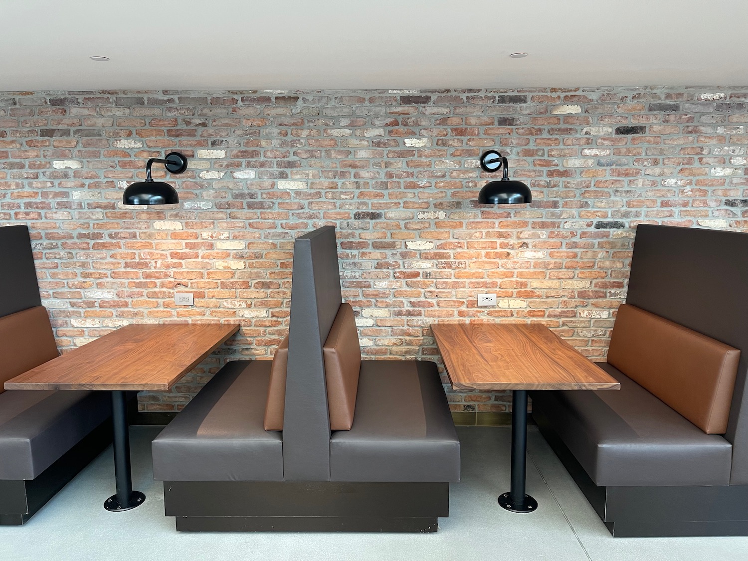 a booth seating in a room with brick wall and lamps