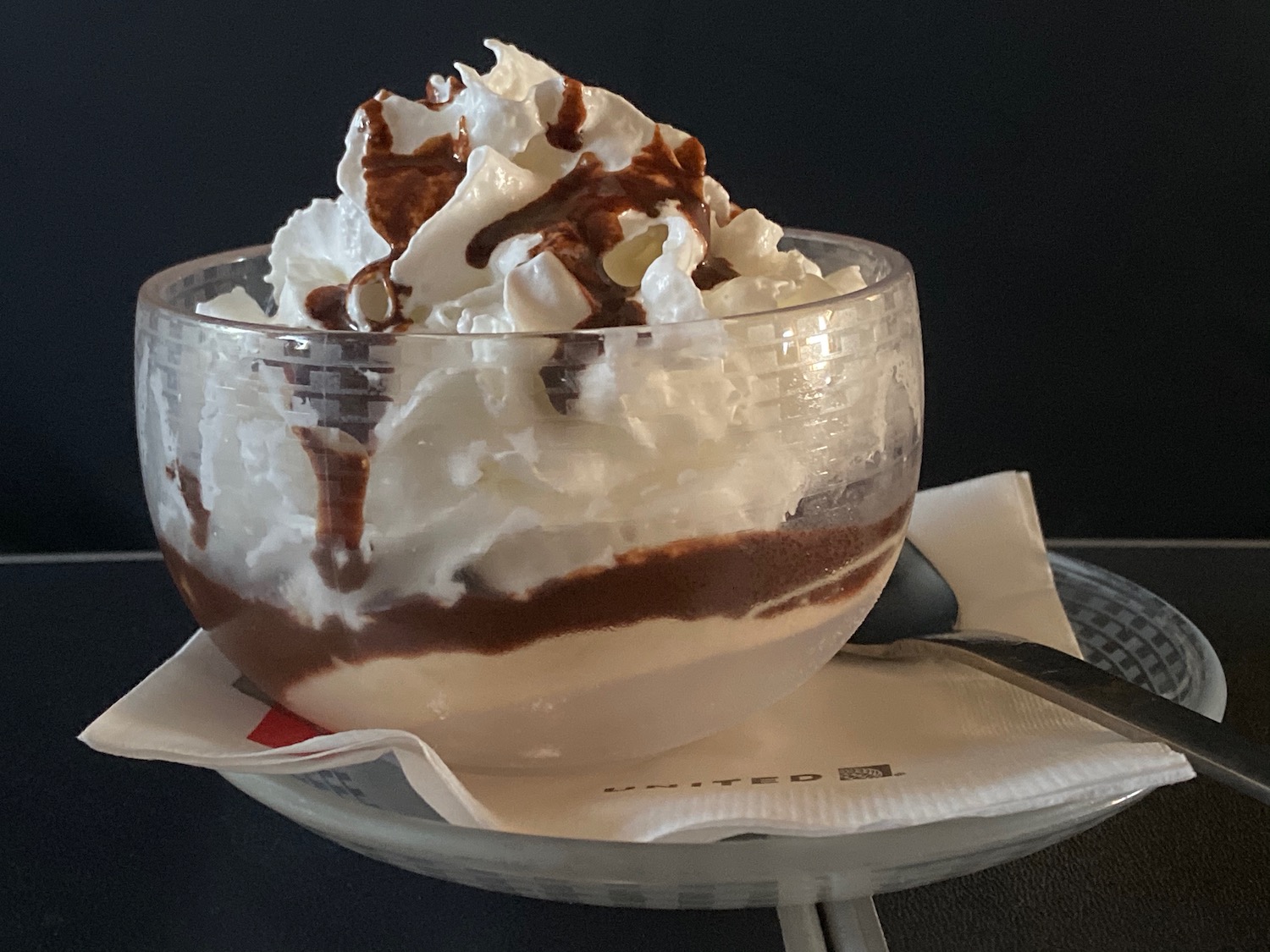 a glass bowl with whipped cream and chocolate syrup