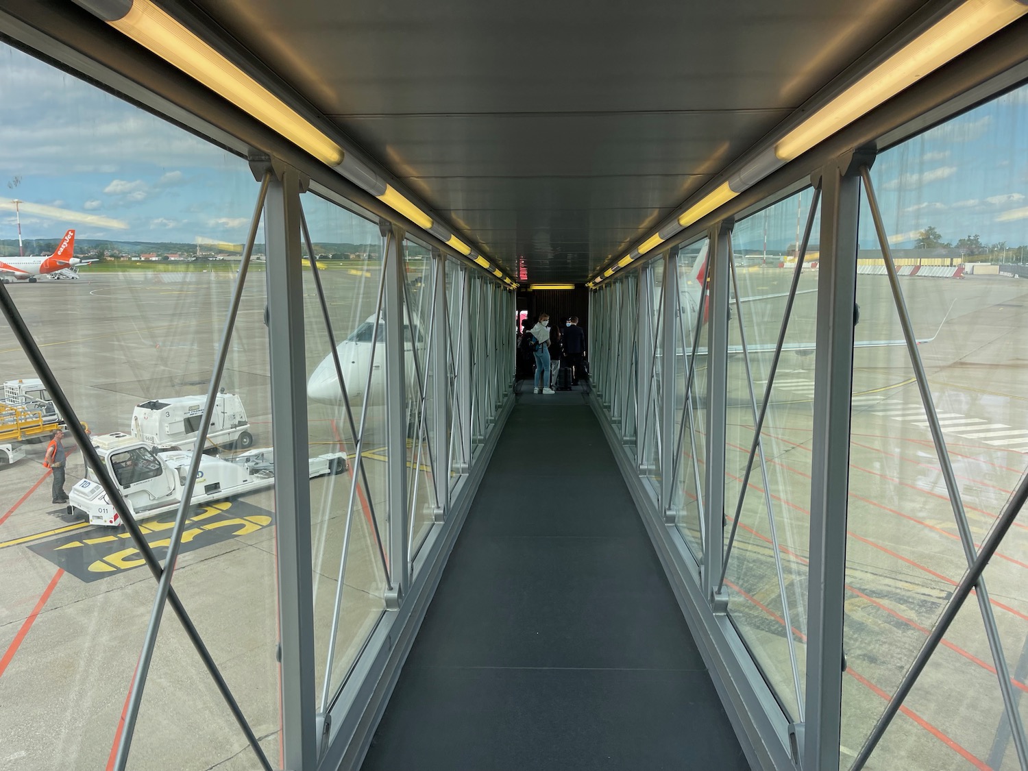 a walkway with glass windows and a plane in the background