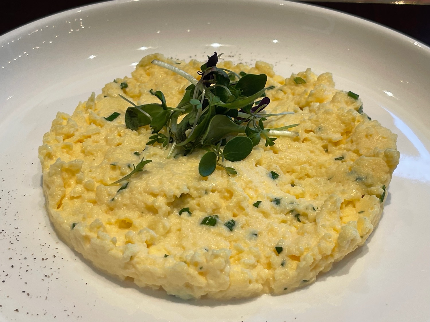 a plate of scrambled eggs with sprouts on top