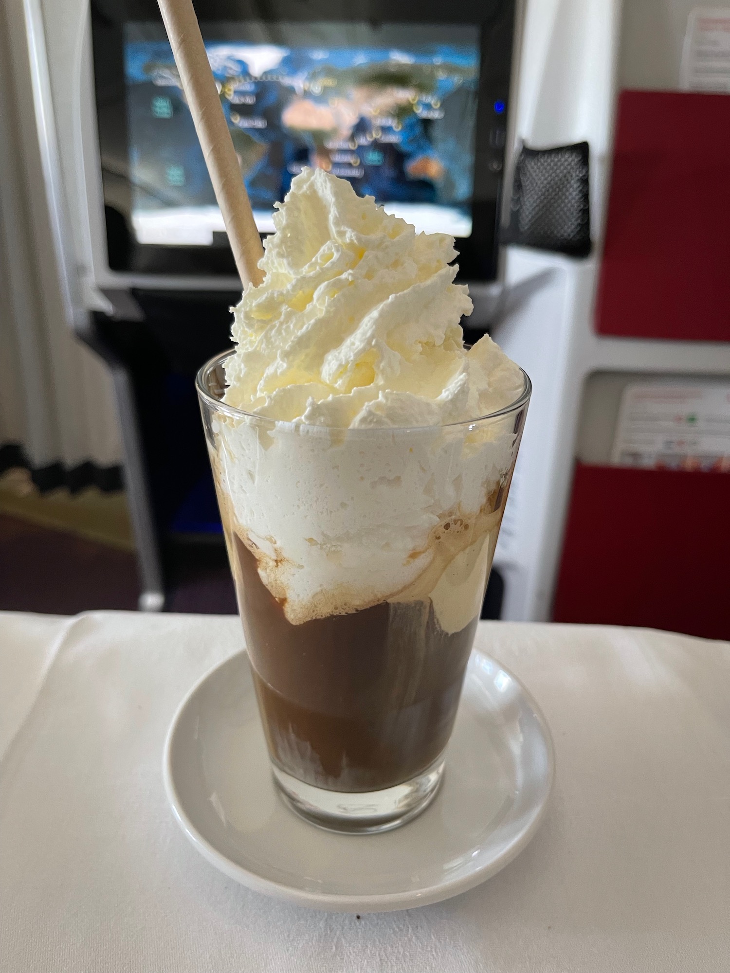 a glass of coffee with whipped cream and a straw