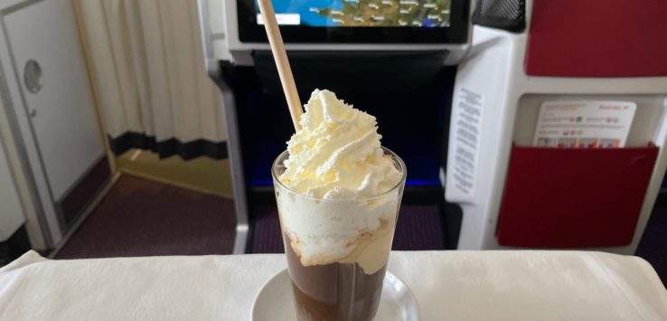 a glass of chocolate milkshake with whipped cream and a wooden stick