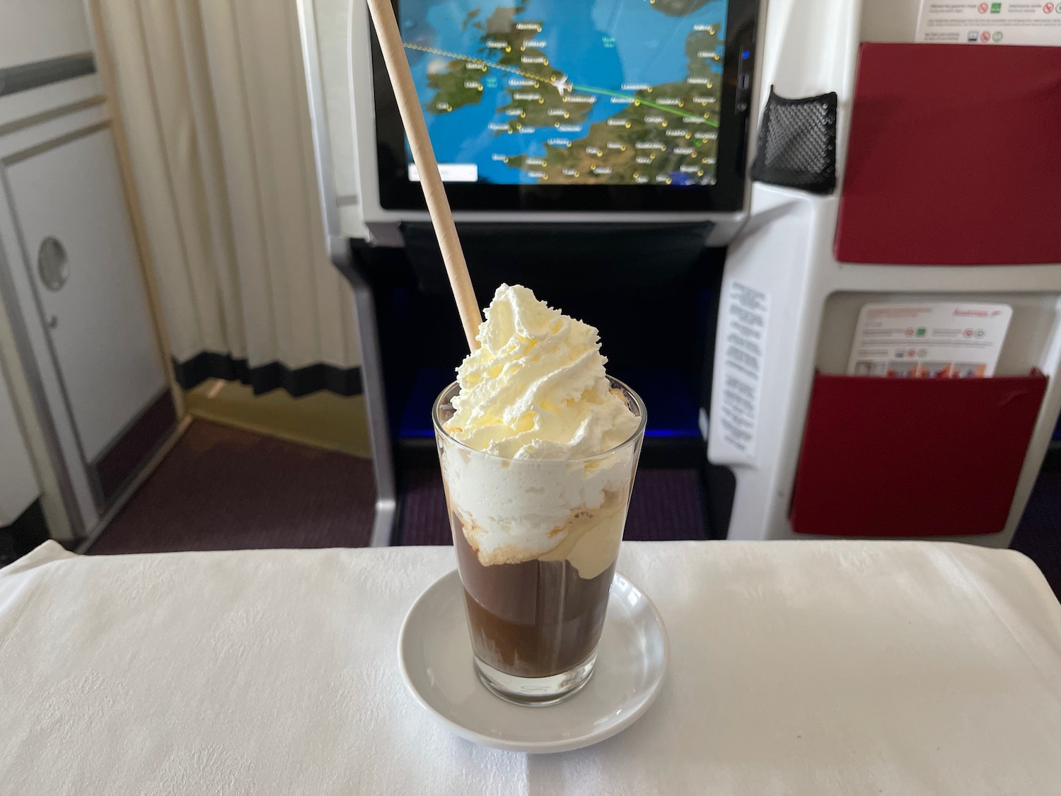 a glass of chocolate milkshake with whipped cream and a wooden stick