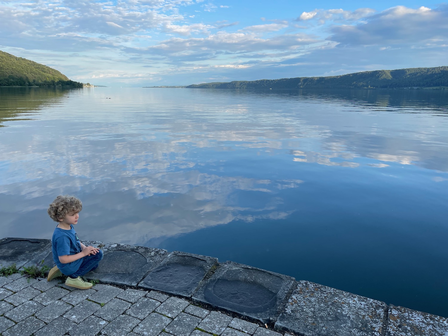 a child sitting on a stone ledge next to a body of water