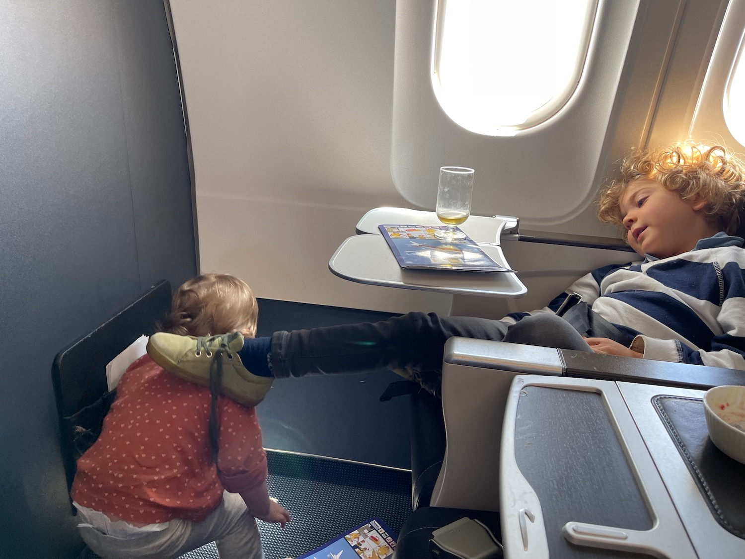 a child kicking another child on an airplane