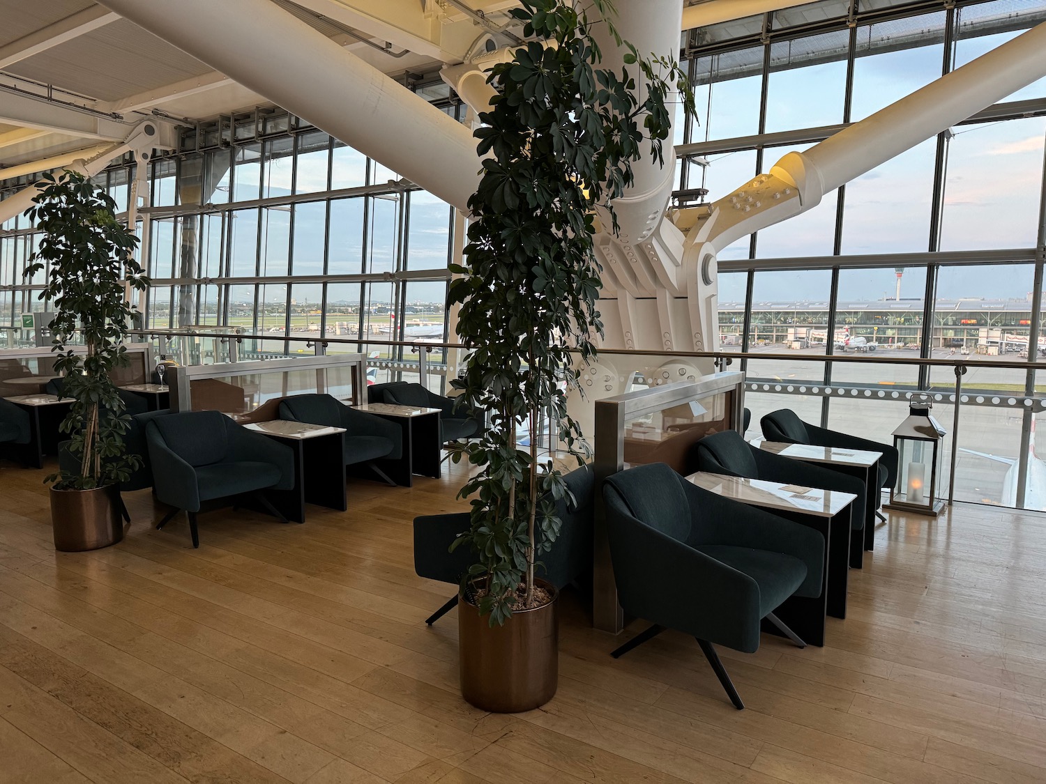 a room with tables and chairs and a tree in front of windows