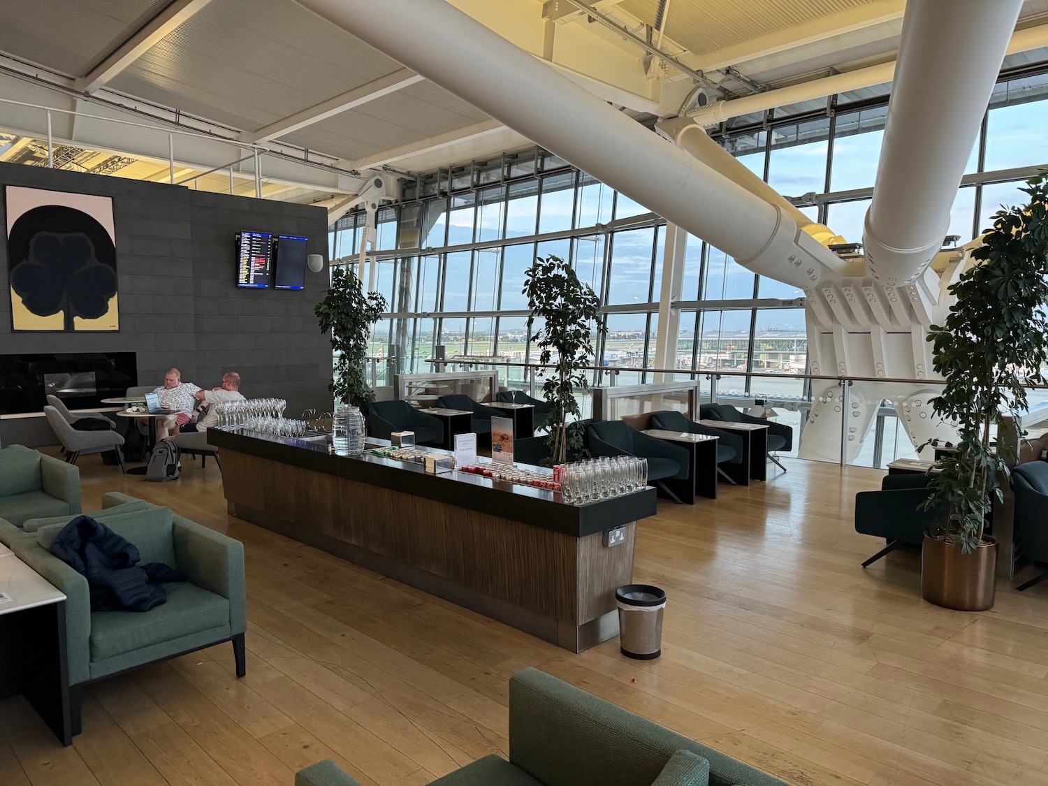 a room with a large window and a bar with chairs and a tv