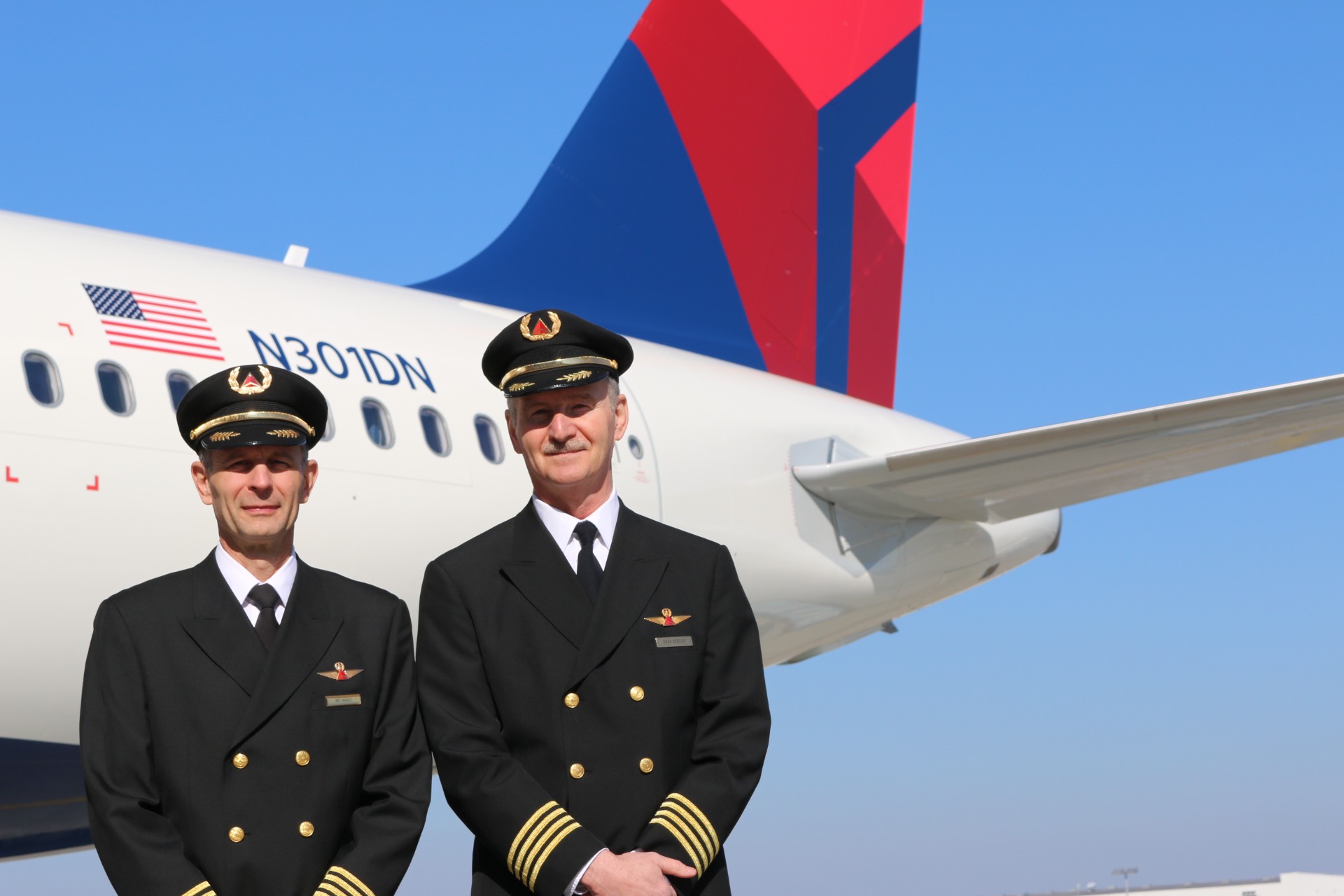 two men in uniform standing in front of an airplane