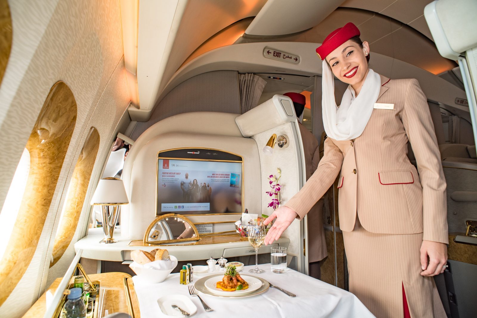 a woman in a suit and hat serving food in a plane