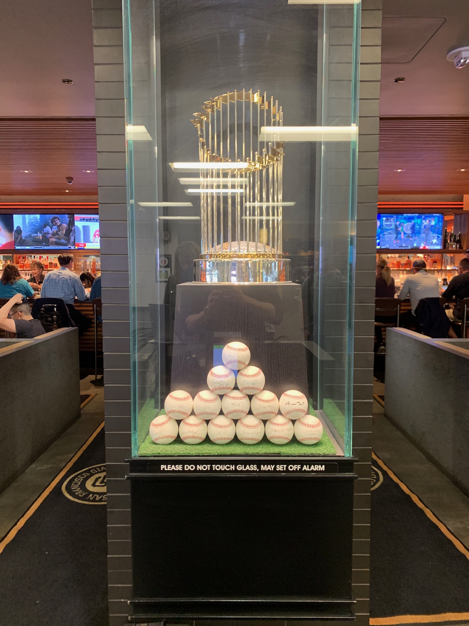 a glass case with a trophy and baseballs in it