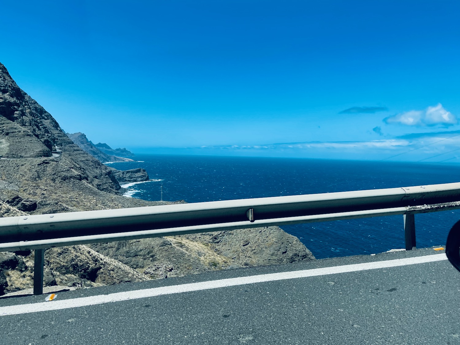 a road with a body of water and mountains