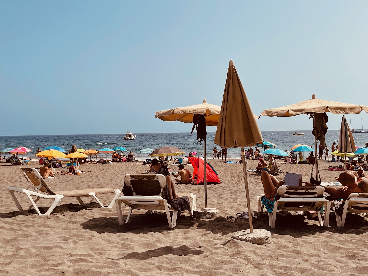 people sitting on a beach with umbrellas and chairs