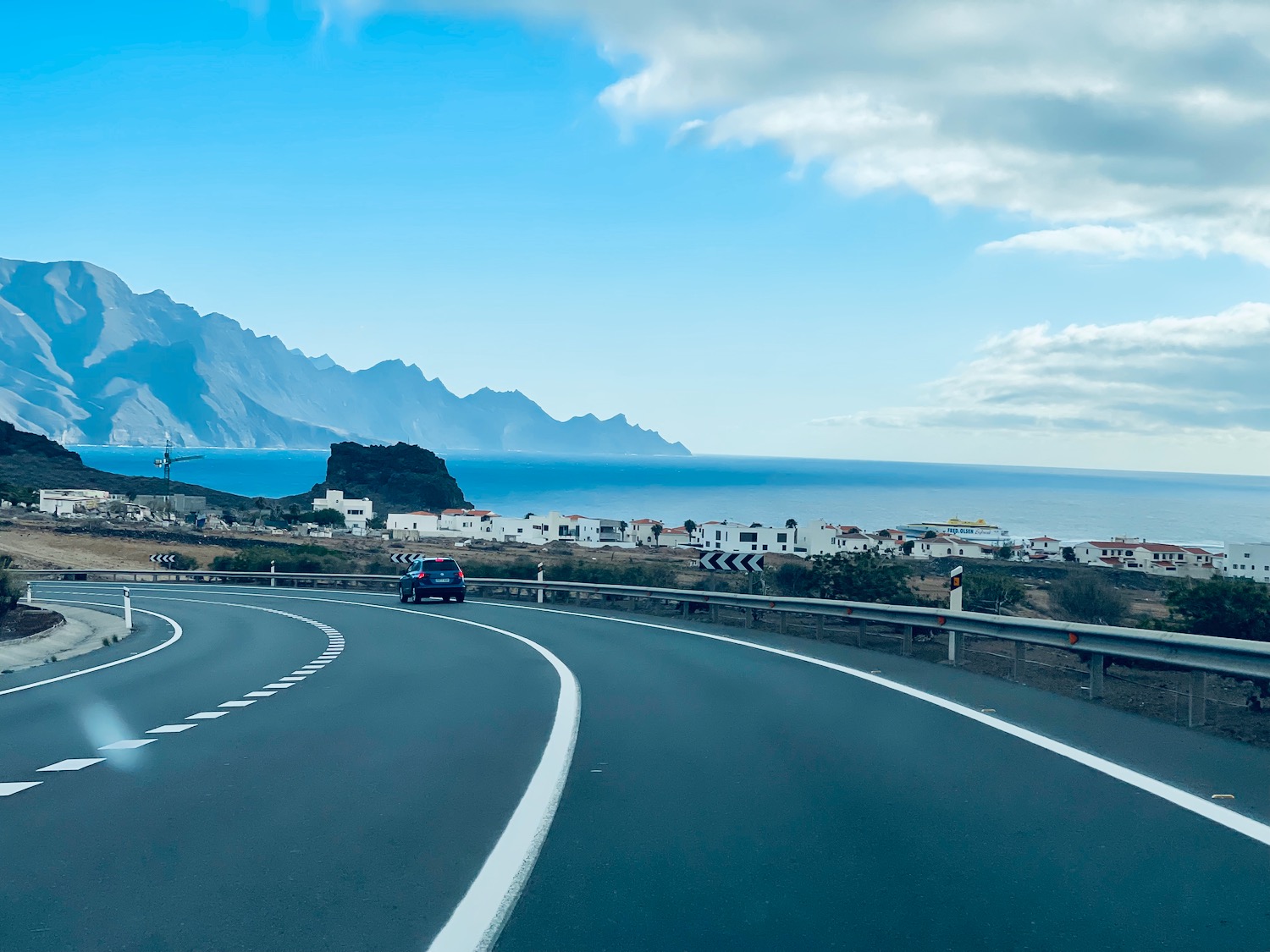 a road with a body of water and mountains in the background