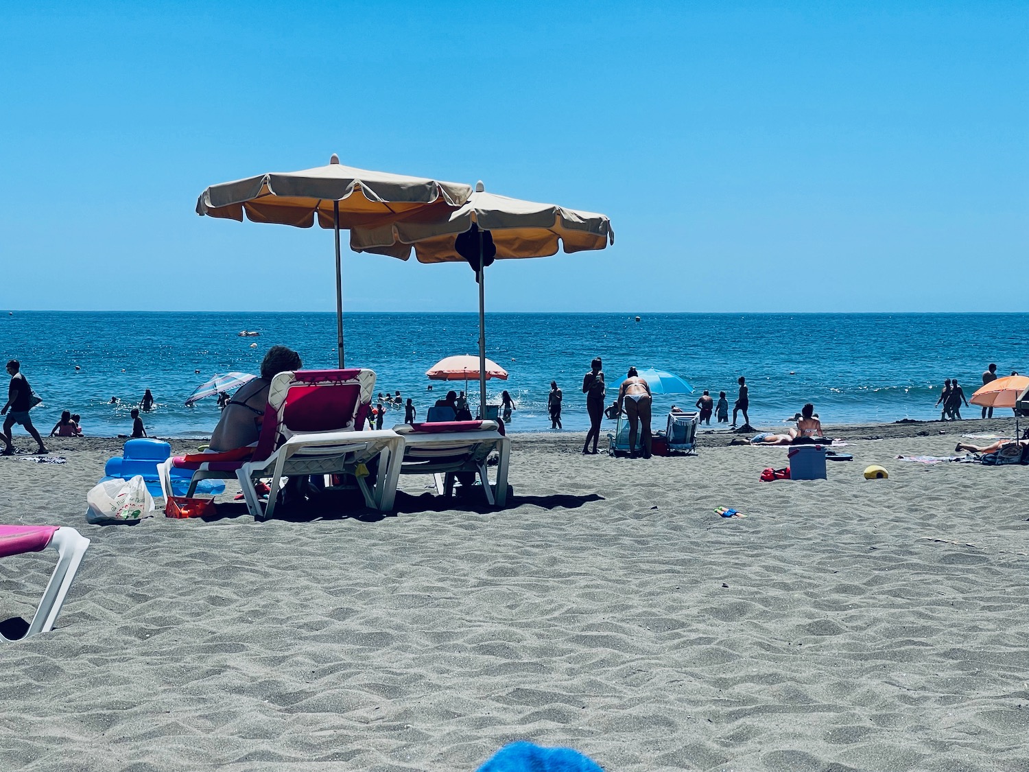 people on a beach with umbrellas and chairs