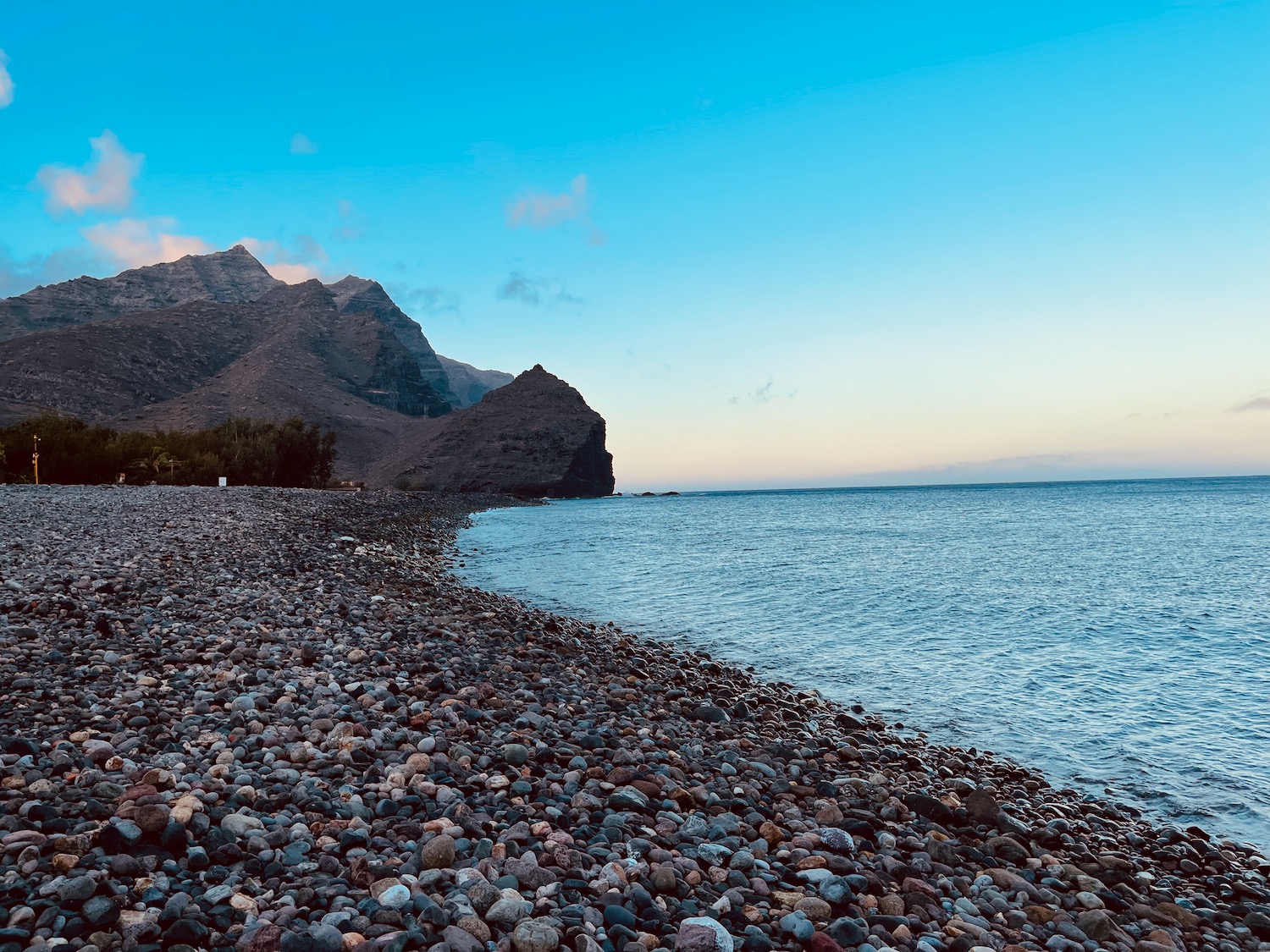 a rocky beach with mountains in the background