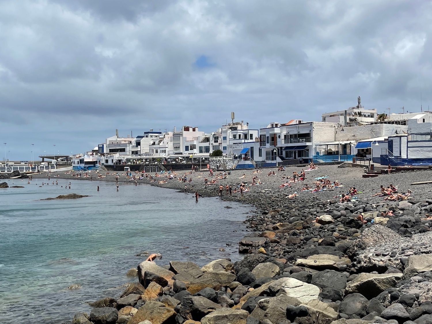 a rocky beach with buildings and a body of water