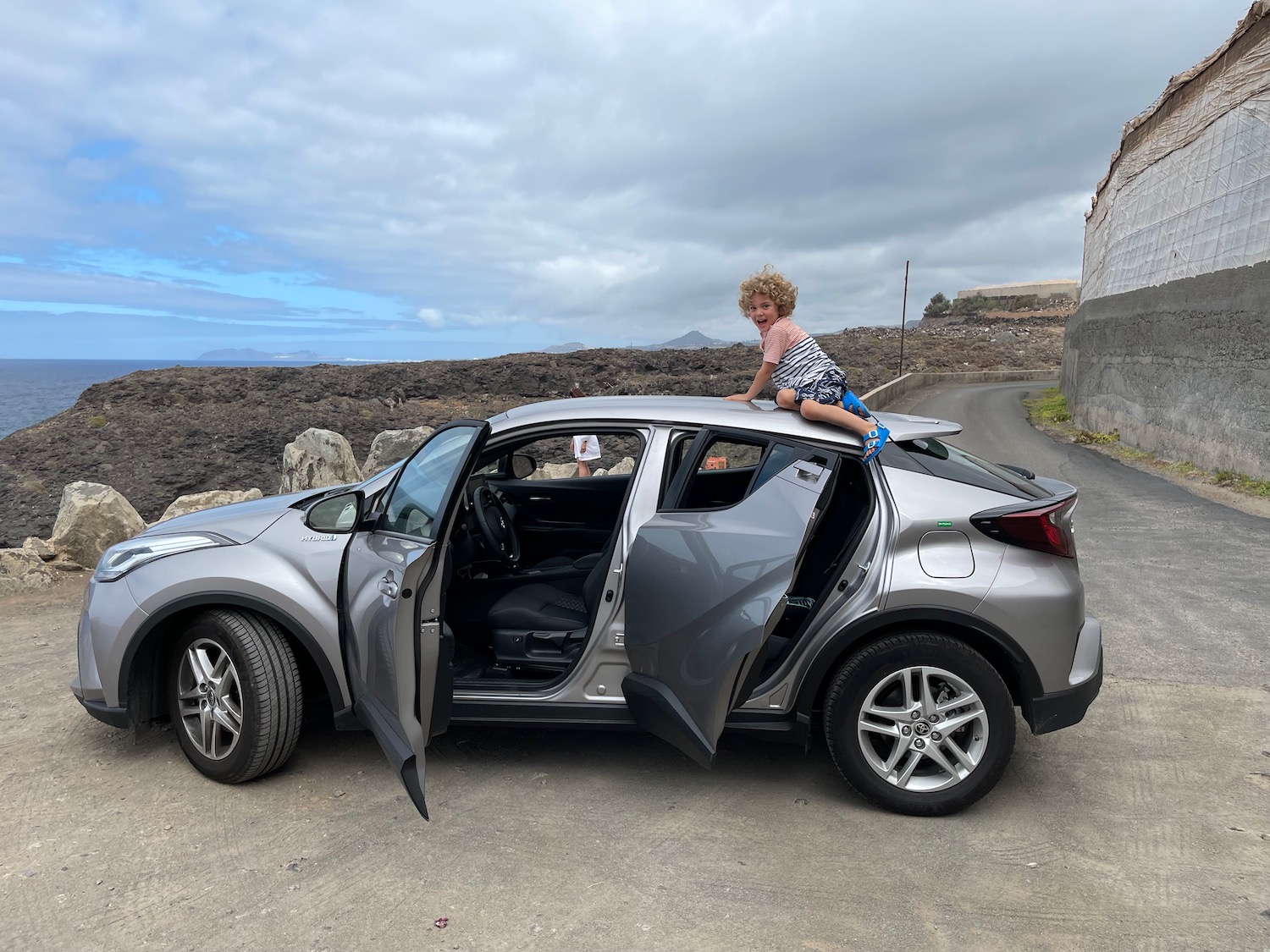 a child sitting on top of a car with the door open