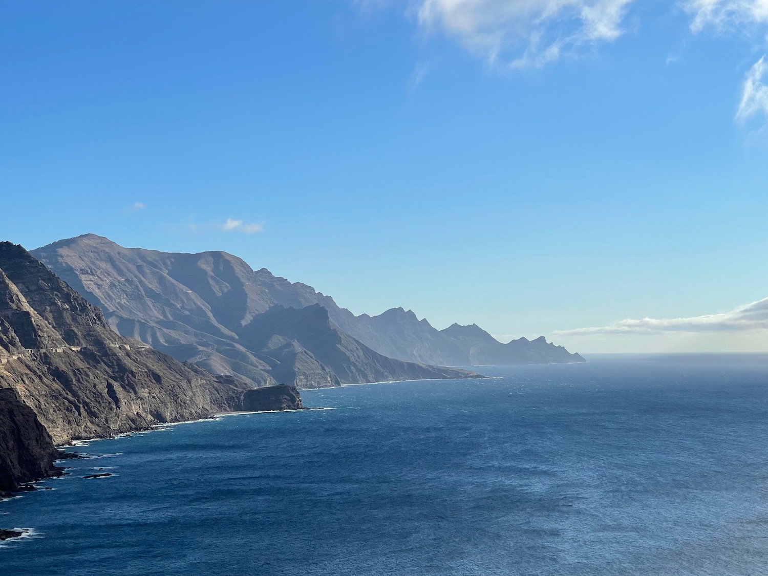 a body of water with mountains and blue sky