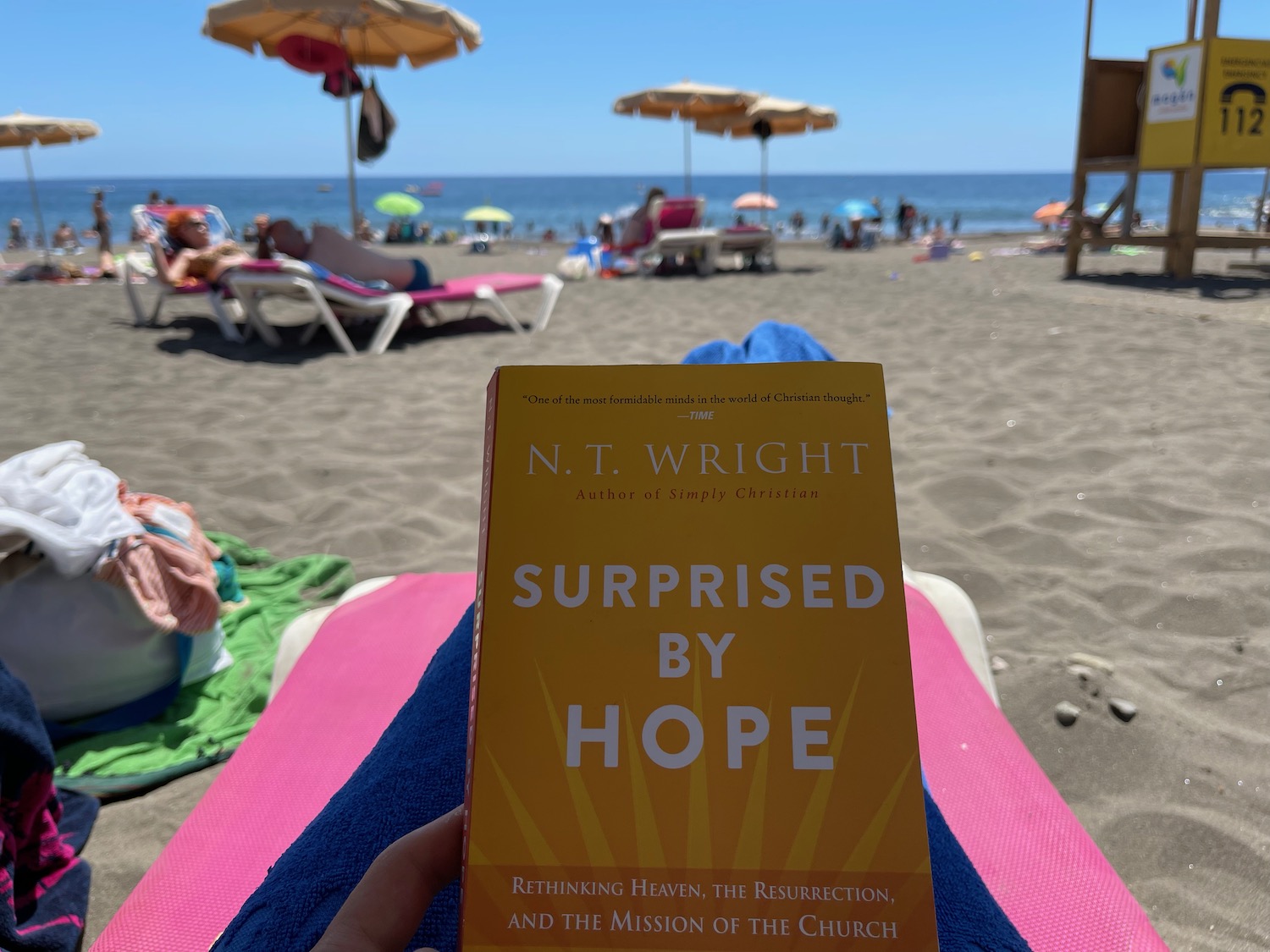 a person holding a book on a beach