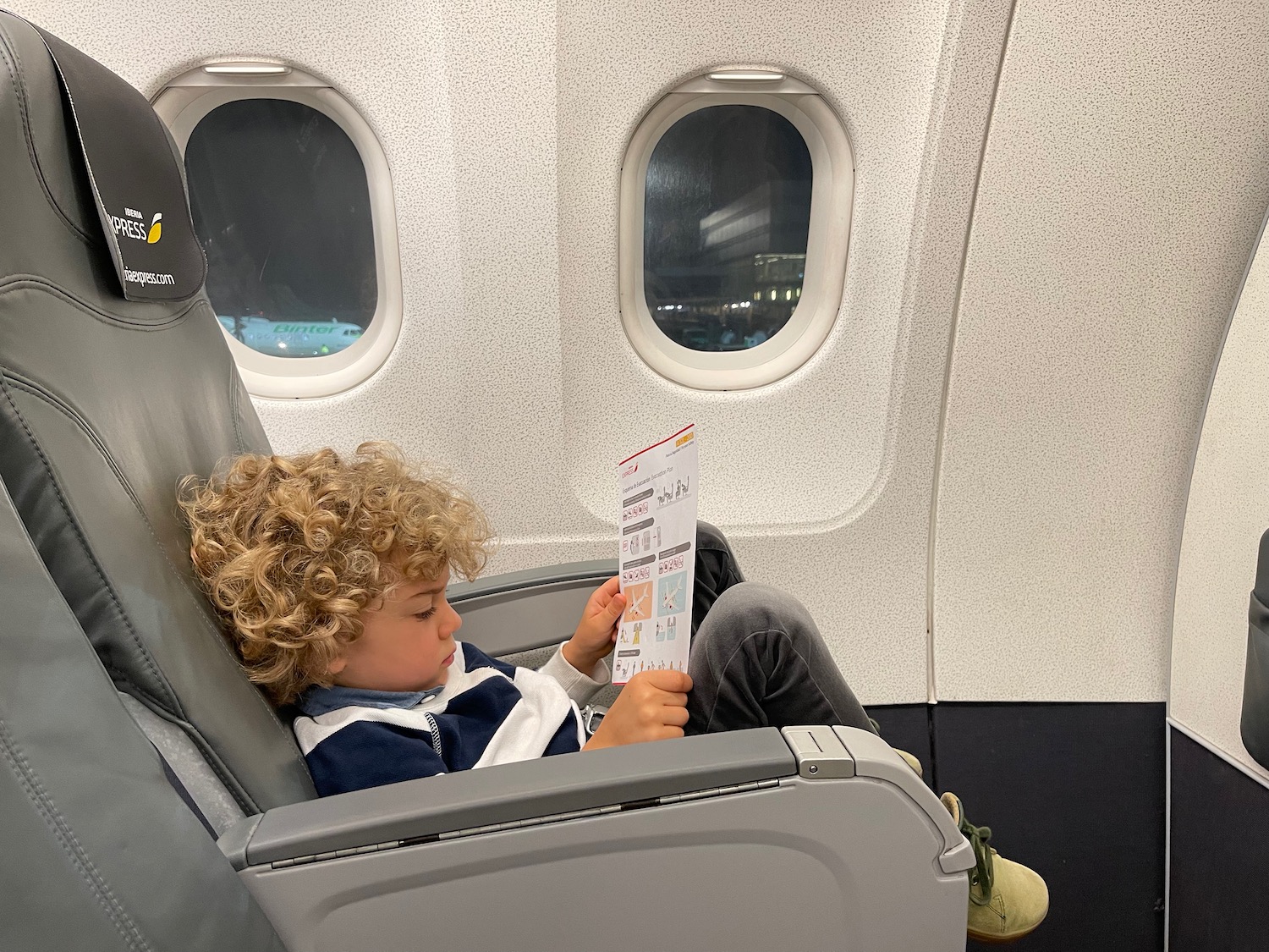 a child sitting in a plane reading a paper