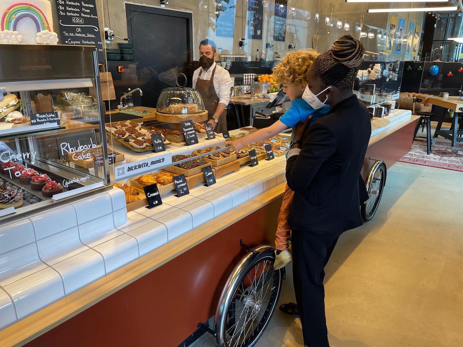 a woman and child standing next to a counter with food