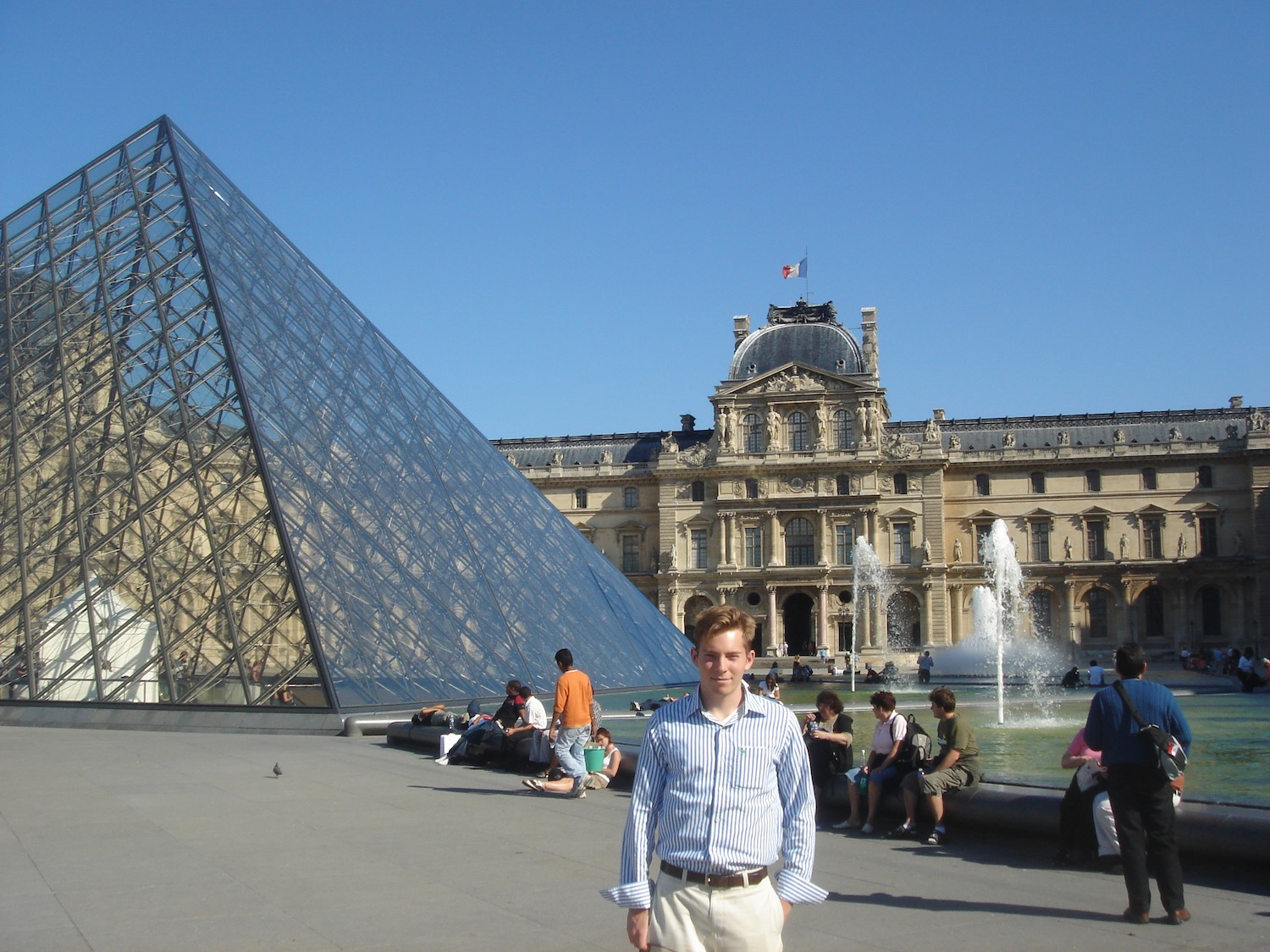 a man standing in front of a glass pyramid