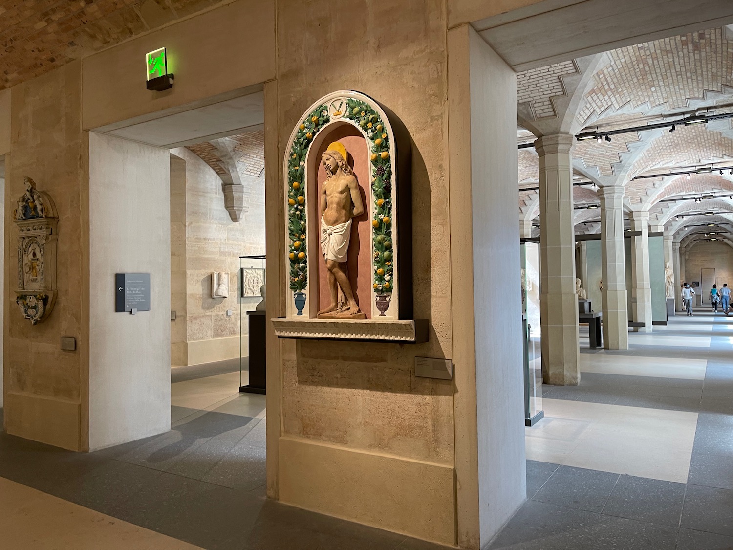 a statue of a man in a room with columns and a green sign