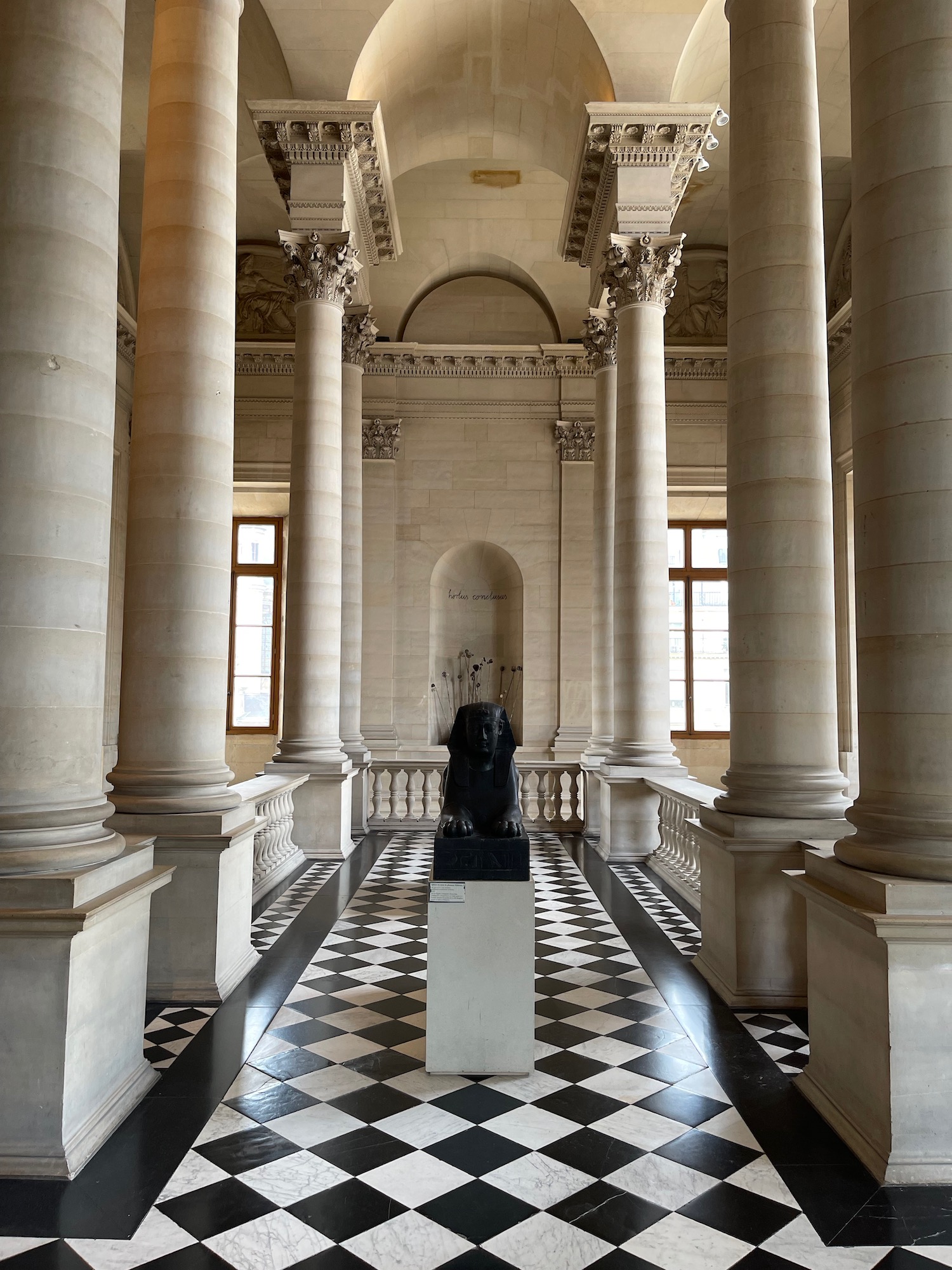 a black statue in a room with columns