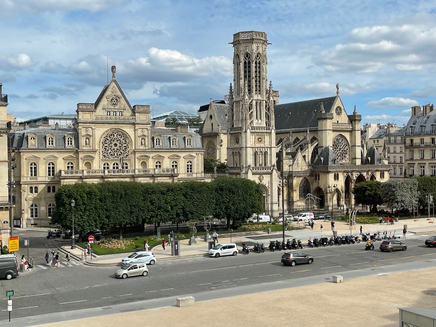 a large building with a tower and a tower and a street with cars and people