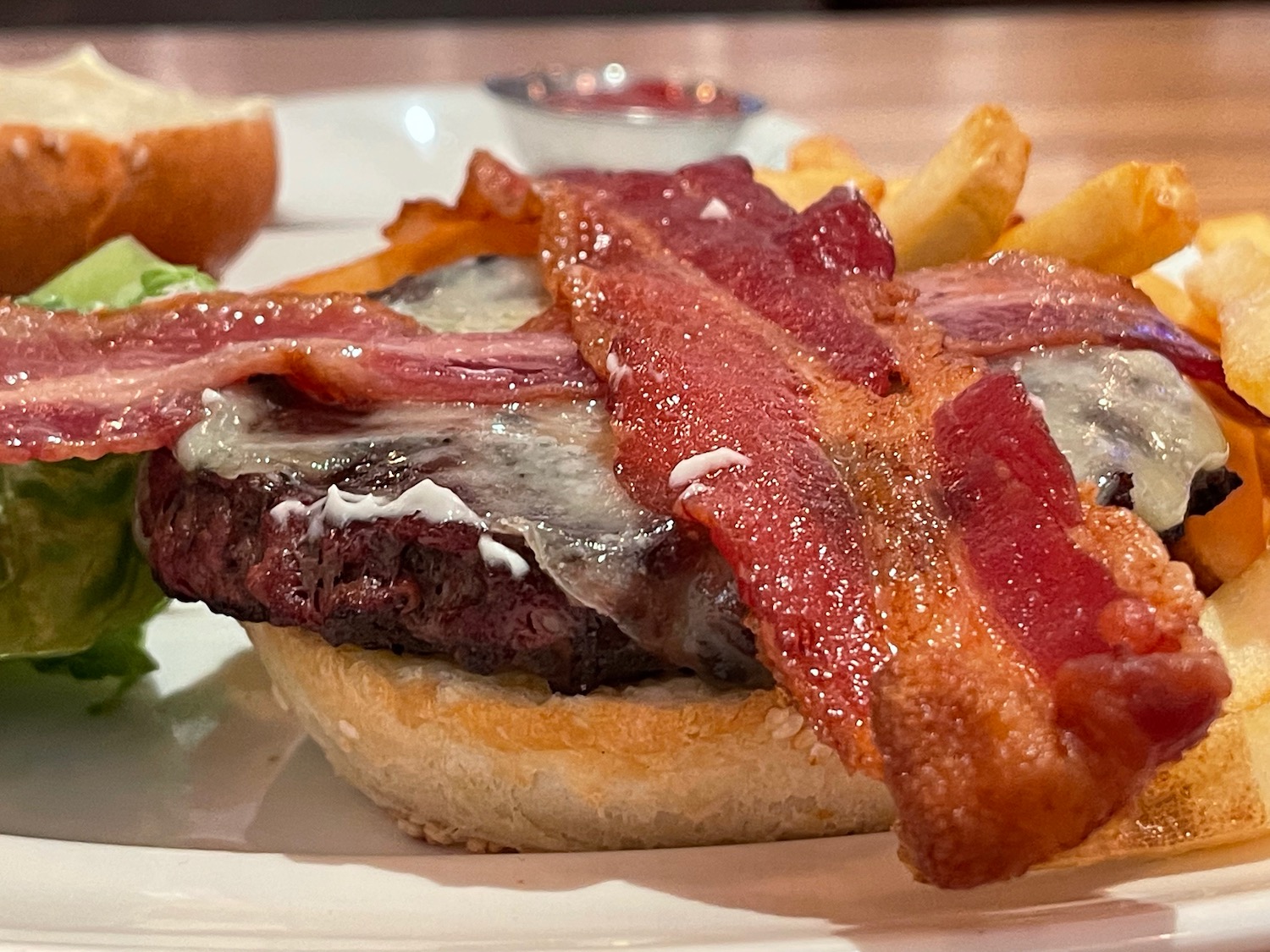 a burger with bacon and fries on a plate